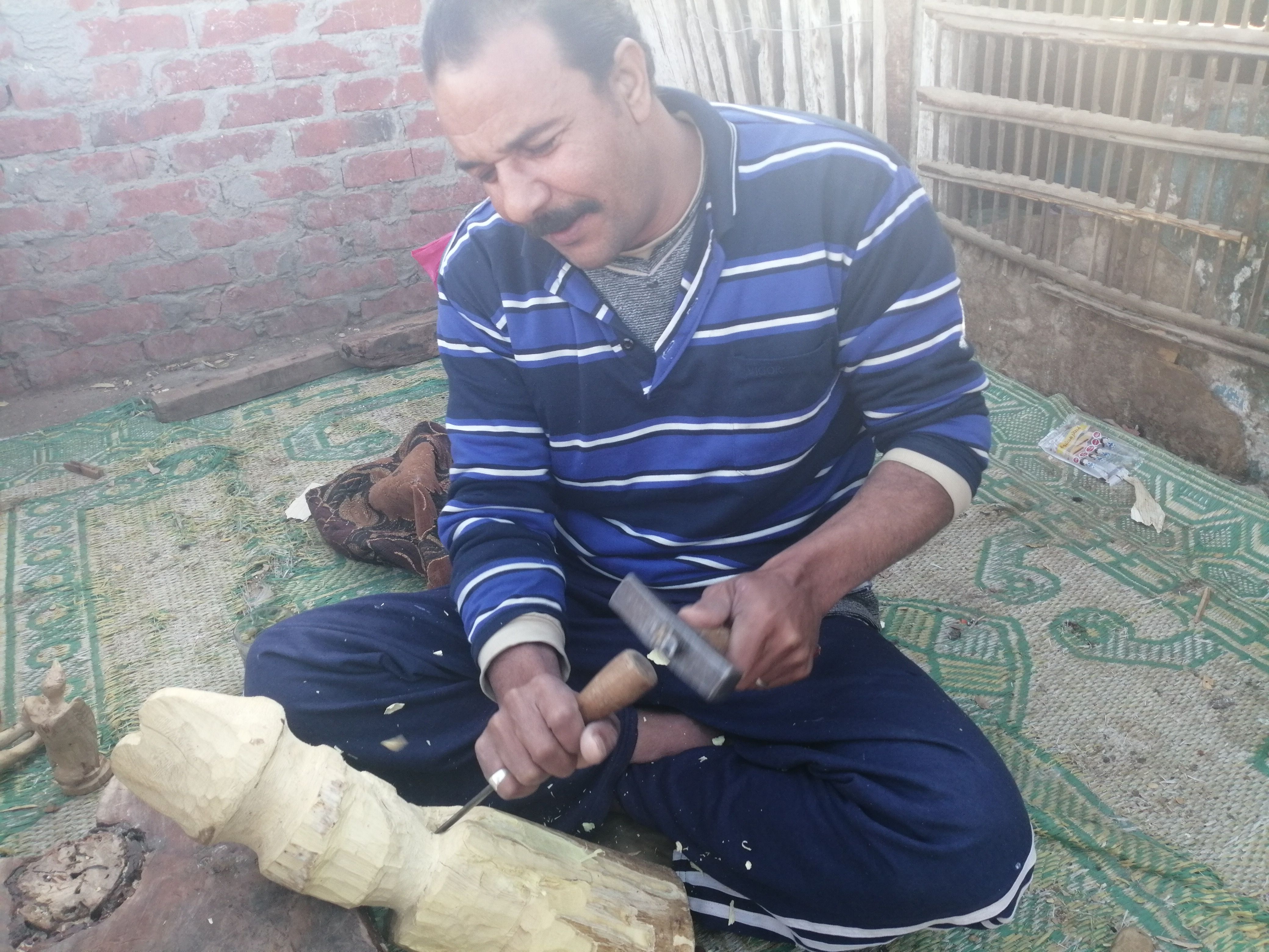 "مفيش مستحيل".. أحمد يتحدى إعاقته بنحت تماثيل خشب على سطح منزله ببنى سويف.. ويؤكد: أصبت...