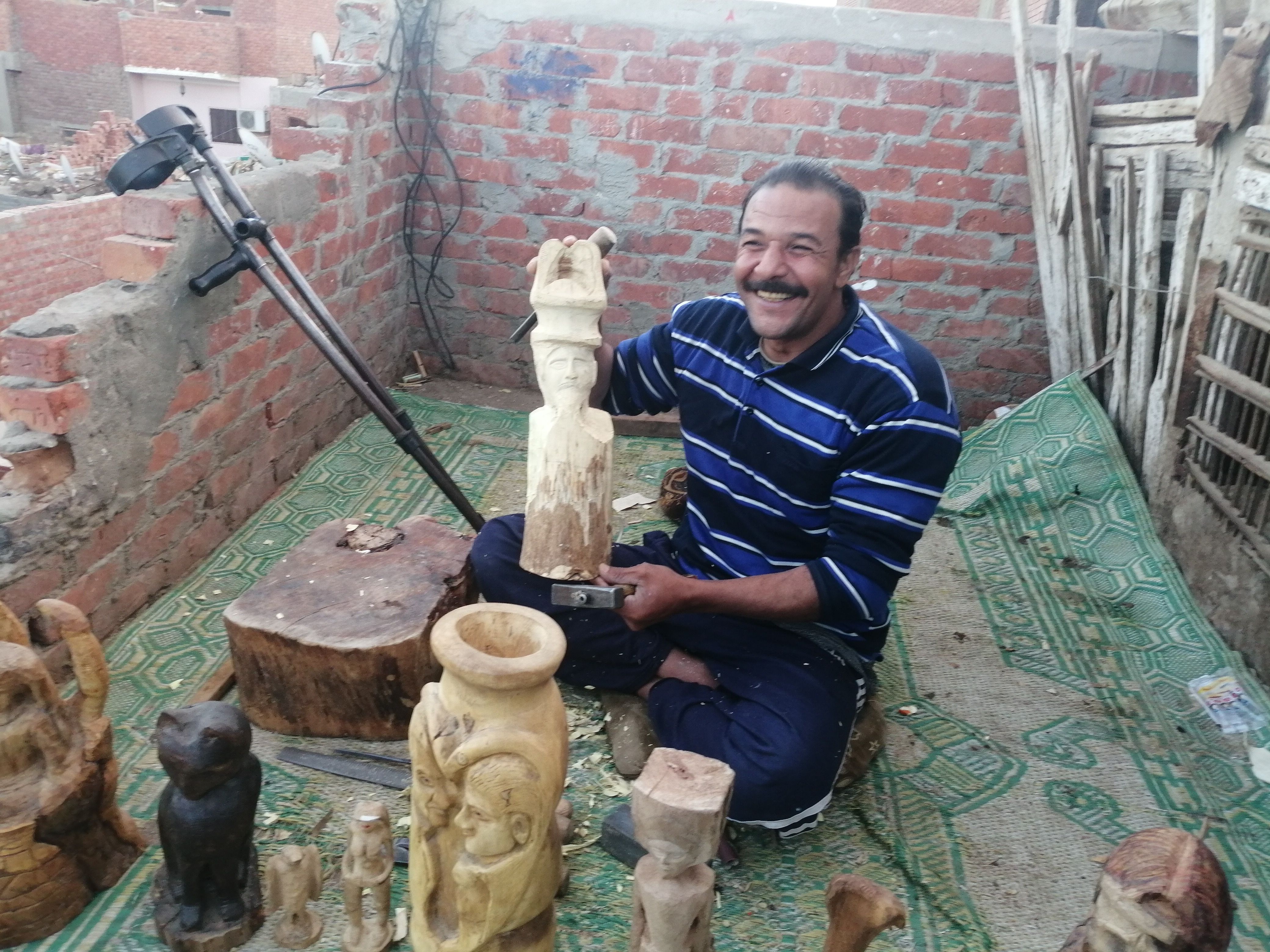 "مفيش مستحيل".. أحمد يتحدى إعاقته بنحت تماثيل خشب على سطح منزله ببنى سويف.. ويؤكد: أصبت...